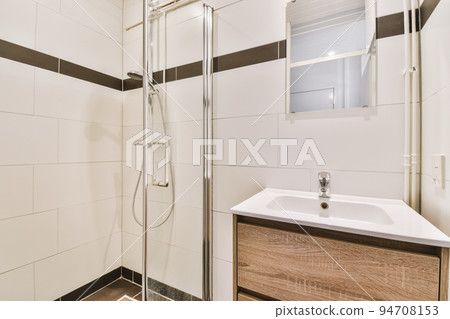 Bathroom with white tiled walls and open shower near sink with toilet in light 94708153