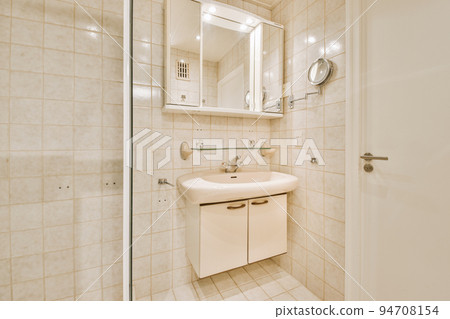 Sinks with mirrors and shower box with glass door in modern bathroom with white tiled walls 94708154