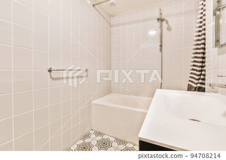 Sinks with mirrors and clean bathtub located near shower box with glass door in modern bathroom with white tiled walls 94708214