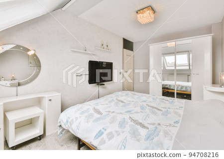 Home interior design of bedroom with bed and wooden wardrobe placed in corner near window in modern apartment 94708216