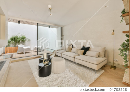 Large soft velvet couch with colorful cushions in living room with wooden parquet and kitchen island under ceiling with beams Large soft velvet couch with colorful cushions in living room with wooden parquet and kitchen island under ceiling with beams 94708228