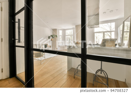 Table with chairs and flowers located near lounge area and kitchen in spacious room of contemporary apartment Table with chairs and flowers located near lounge area and kitchen in spacious room of contemporary apartment 94708327