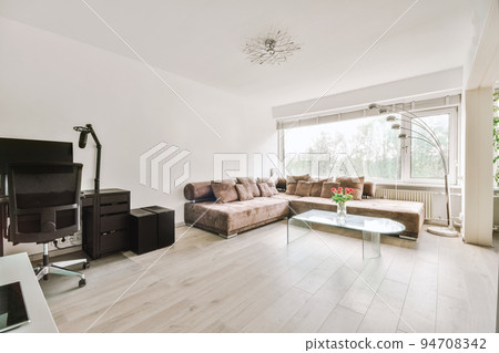 Comfortable sofa with cushions placed against light wall with TV and decorations in modern loving room Comfortable sofa with cushions placed against light wall with TV and decorations in modern loving room 94708342