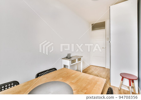 Wooden table with vase of flowers with wardope in modern living room near window 94708356