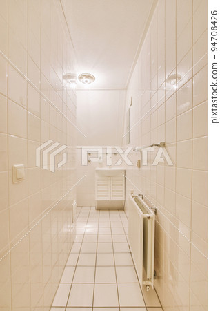 Wall hung toilet and small sink in corner in lavatory room with beige tile 94708426