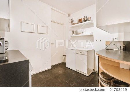Well organized small home kitchen interior with sink under window and light furniture with stove and fridge in urban apartment Well organized small home kitchen interior with sink under window and light furniture with stove and fridge in urban apartment 94708439