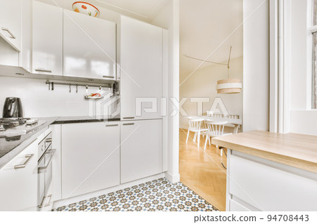 Well organized small home kitchen interior with sink under window and light furniture with stove and fridge in urban apartment Well organized small home kitchen interior with sink under window and light furniture with stove and fridge in urban apartment 94708443
