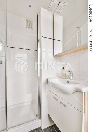 Sinks with mirrors and shower box with glass door in modern bathroom with white tiled walls 94708466