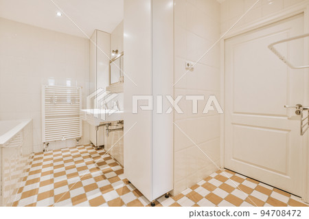 Sinks with mirrors and clean bathtub located near shower box with glass door in modern bathroom with white tiled walls Sinks with mirrors and clean bathtub located near shower box with glass door in modern bathroom with white tiled walls 94708472