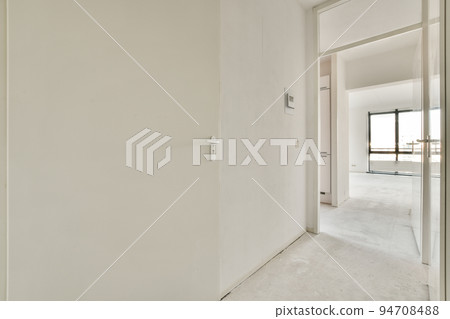 Light narrow hallway with many doors in white walls over lumber floor 94708488