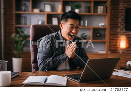 Happy adult japanese man look at laptop, gesturing and greeting, have video call with client Happy adult japanese man look at laptop, gesturing and greeting, have video call with client 94708577