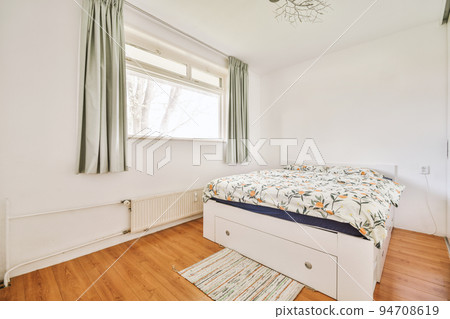 Home interior design of bedroom with bed and wooden wardrobe placed in corner near window in modern apartment Home interior design of bedroom with bed and wooden wardrobe placed in corner near window in modern apartment 94708619