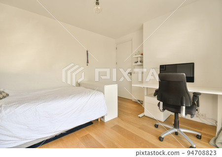 Modern bed with comfortable mattress and soft pillows located near bedside table and computer in spacious bedroom 94708823