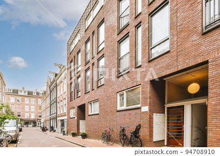 Panorama view of brick houses from an empty sidewalk street with cars, trees and lanterns Panorama view of brick houses from an empty sidewalk street with cars, trees and lanterns 94708910
