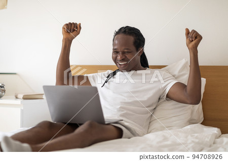 Great News. Joyful African American Man Celebrating Success With Laptop In Bed 94708926