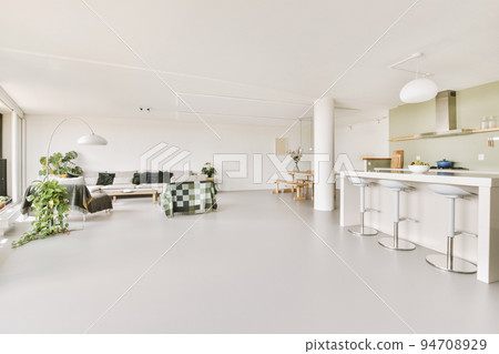 Contemporary minimalist style interior design of light studio apartment with wooden table and chairs in dining zone between open kitchen and living room with white walls and parquet floor Contemporary minimalist style interior design of light studio apartment with wooden table and chairs in dining zone between open kitchen and living room with white walls and parquet floor 94708929