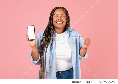 Joyful African American Lady Holding Cellphone Shaking Fists, Pink Background 94709020