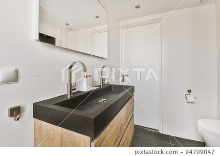 Flush toilet located between sink and shower in small tiled bathroom of contemporary apartment Flush toilet located between sink and shower in small tiled bathroom of contemporary apartment 94709047
