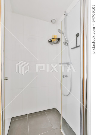Shower faucets attached to tiled wall near glass partition and ornamental curtail in washroom at home Shower faucets attached to tiled wall near glass partition and ornamental curtail in washroom at home 94709103