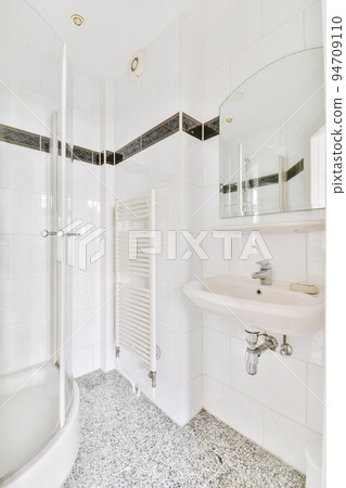 Sinks with mirrors and shower box with glass door in modern bathroom with white tiled walls Sinks with mirrors and shower box with glass door in modern bathroom with white tiled walls 94709110