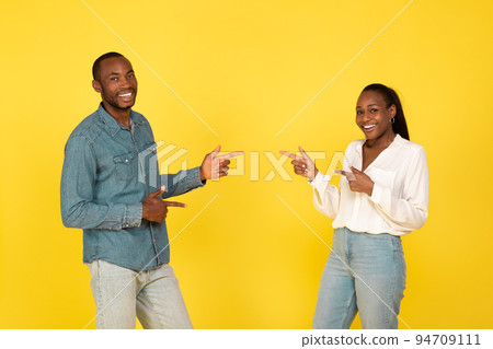 Happy Black Spouses Pointing Fingers Choosing Each Other, Yellow Background Happy Black Spouses Pointing Fingers Choosing Each Other, Yellow Background 94709111