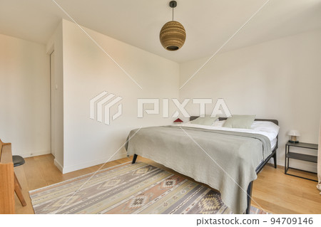 Stylish simple interior of bedroom with brick wall and wooden bed under white ceiling with beams 94709146