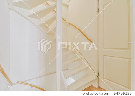 White hallway with wooden stairway leading to second floor of modern luxury apartment with minimalist interior design White hallway with wooden stairway leading to second floor of modern luxury apartment with minimalist interior design 94709155