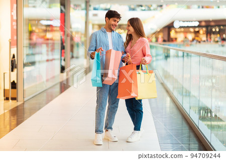 Cheerful Couple Holding Shopping Bags Buying Clothes Standing In Mall Cheerful Couple Holding Shopping Bags Buying Clothes Standing In Mall 94709244