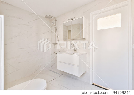 Modern flush toilet,shower box and ceramic sink installed on white tiled walls near mirror and towel in small restroom at home Modern flush toilet,shower box and ceramic sink installed on white tiled walls near mirror and towel in small restroom at home 94709245