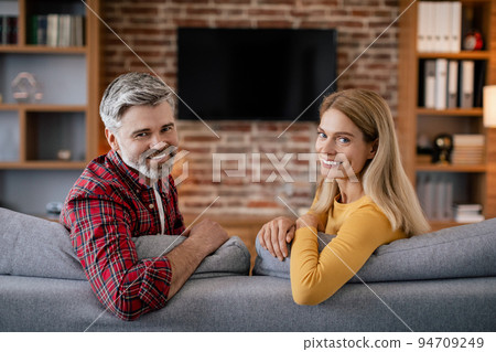 Calm smiling mature european wife and husband relaxing, enjoy free time with tv with blank screen Calm smiling mature european wife and husband relaxing, enjoy free time with tv with blank screen 94709249