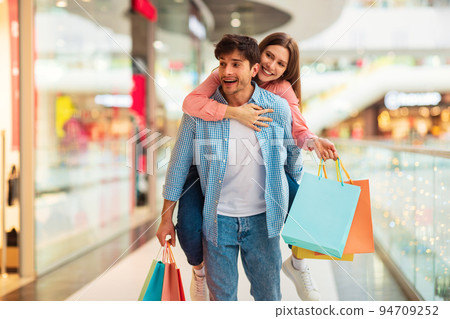 Couple Shopping Together Having Fun Buying New Clothes In Mall Couple Shopping Together Having Fun Buying New Clothes In Mall 94709252
