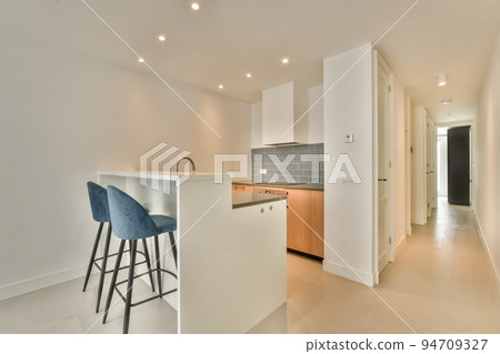 Contemporary counters and stools located under stylish exhaust hood in spacious light kitchen at home Contemporary counters and stools located under stylish exhaust hood in spacious light kitchen at home 94709327