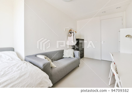 Home interior design of bedroom with bed and wooden wardrobe placed in corner near window in modern apartment Home interior design of bedroom with bed and wooden wardrobe placed in corner near window in modern apartment 94709382