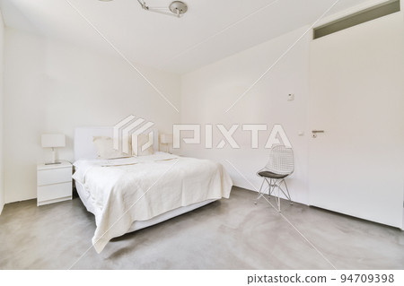 Home interior design of bedroom with bed and wooden wardrobe placed in corner near window in modern apartment Home interior design of bedroom with bed and wooden wardrobe placed in corner near window in modern apartment 94709398