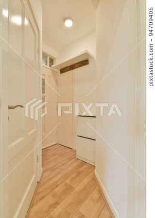 Perspective view of empty narrow hallway with white walls and wardrobe with mirror and parquet floor in minimalist style apartment Perspective view of empty narrow hallway with white walls and wardrobe with mirror and parquet floor in minimalist style apartment 94709408