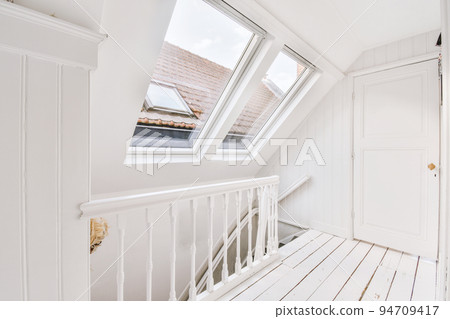 Closed white door of room located near framed pictures and stylish lamp on top of stairway at home 94709417