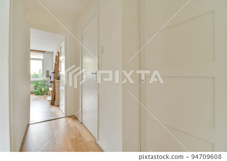 Perspective view of empty narrow hallway with white walls and wardrobe with mirror and parquet floor in minimalist style apartment Perspective view of empty narrow hallway with white walls and wardrobe with mirror and parquet floor in minimalist style apartment 94709608
