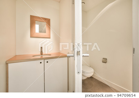 Table with chairs and flowers located near lounge area and kitchen in spacious room of contemporary apartment 94709654