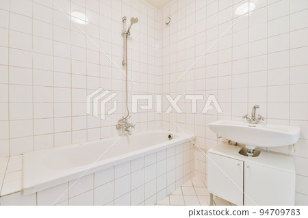 Sinks with mirrors and clean bathtub in modern bathroom with white tiled walls 94709783