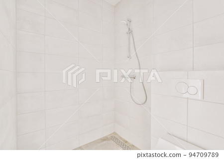 Shower faucets attached to tiled wall near glass partition and ornamental curtail in washroom at home Shower faucets attached to tiled wall near glass partition and ornamental curtail in washroom at home 94709789