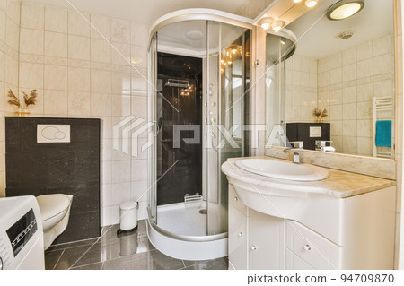 Sinks with mirrors and clean toilet located near shower box with glass door in modern bathroom with white tiled walls 94709870