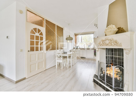 Contemporary minimalist style interior design of light studio apartment with wooden table and chairs in dining zone between open kitchen and living room with white walls and parquet floor 94709880