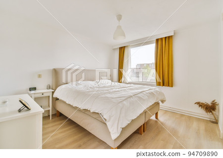 Home interior design of bedroom with bed and wooden wardrobe placed in corner near window in modern apartment 94709890