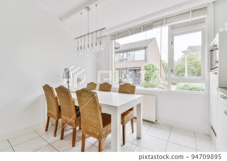 Home interior design of modern loft apartment with open kitchen in minimalist style and spacious dining zone with table and chairs 94709895