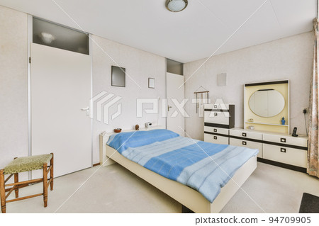 Home interior design of bedroom with bed and wooden wardrobe placed in corner near window in modern apartment Home interior design of bedroom with bed and wooden wardrobe placed in corner near window in modern apartment 94709905