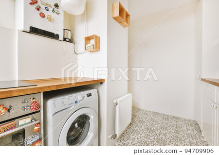 Fragment of interior of light narrow home kitchen with minimalist style white furniture with sink and stove Fragment of interior of light narrow home kitchen with minimalist style white furniture with sink and stove 94709906