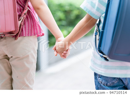 Elementary school students holding hands and walking on the sidewalk 94710514