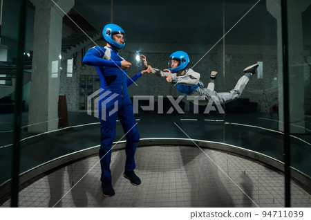 A man teaches a woman how to fly in a wind tunnel. Free fall simulator. A man teaches a woman how to fly in a wind tunnel. Free fall simulator. 94711039