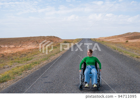 Woman in a wheelchair on a highway in the steppes.  94711095