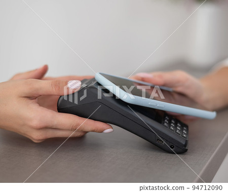 A woman pays using a non -contact payment of the NFC used by a smartphone.  94712090